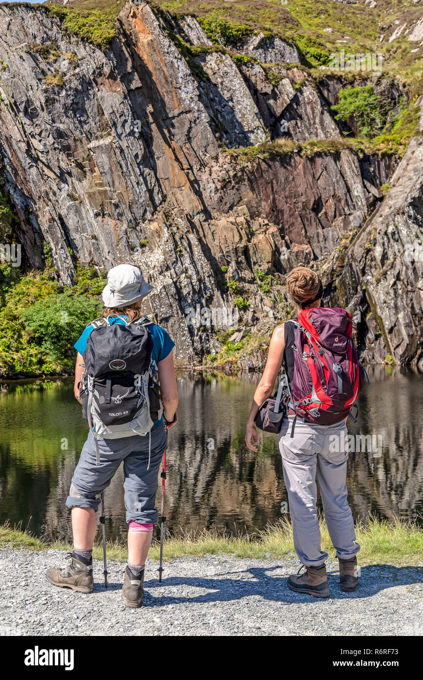 Two female hikers looking at a disused and flooded slate quarry situated on the track up to Moel Siabod, a mountain in the Snowdonia National Park. Stock Photo