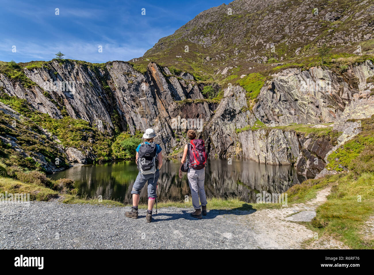 Two female hikers looking at a disused and flooded slate quarry situated on the track up to Moel Siabod, a mountain in the Snowdonia National Park. Stock Photo