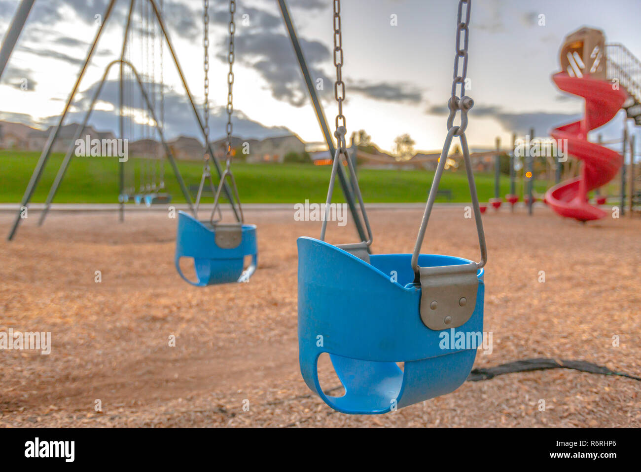 Playground with baby swing and slide near homes Stock Photo Alamy