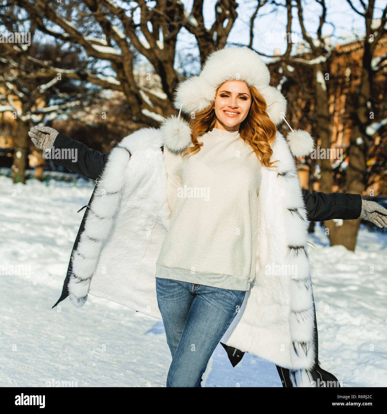 Winter beauty. Young happy woman wearing winter coat and hat outdoors ...