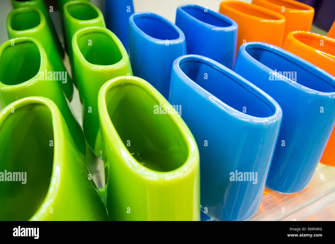 Multi-colored ceramic toothbrush stands on the shelf Stock Photo