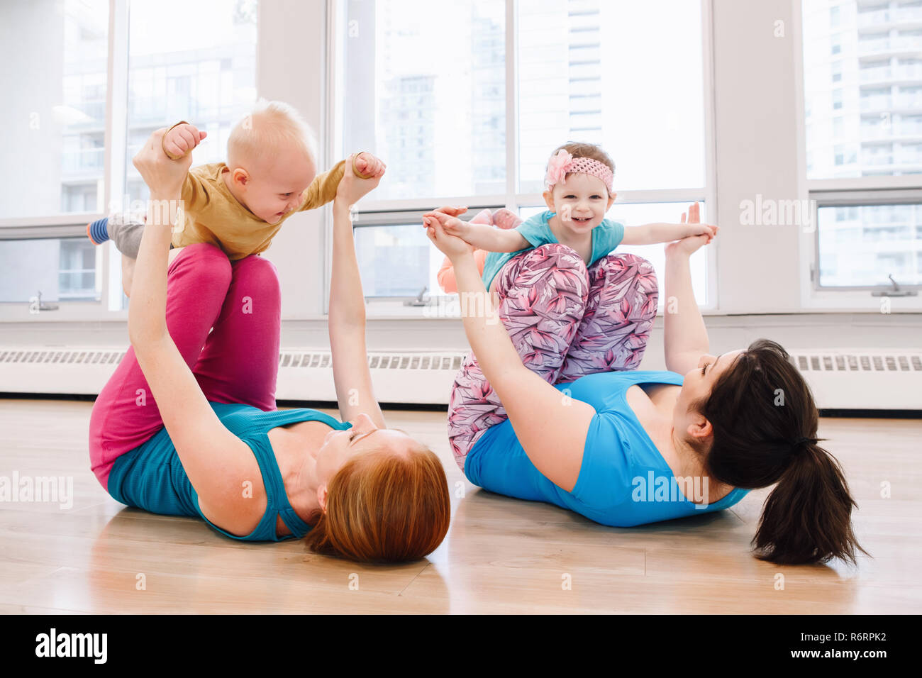 Group of two young women with children doing workout in gym class