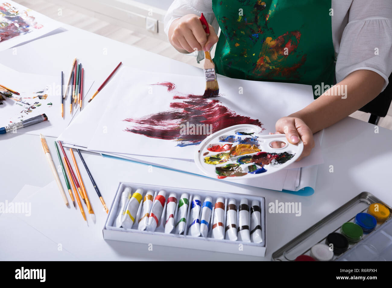 Artist Holding Paint Palette While Painting On Canvas Paper Stock Photo