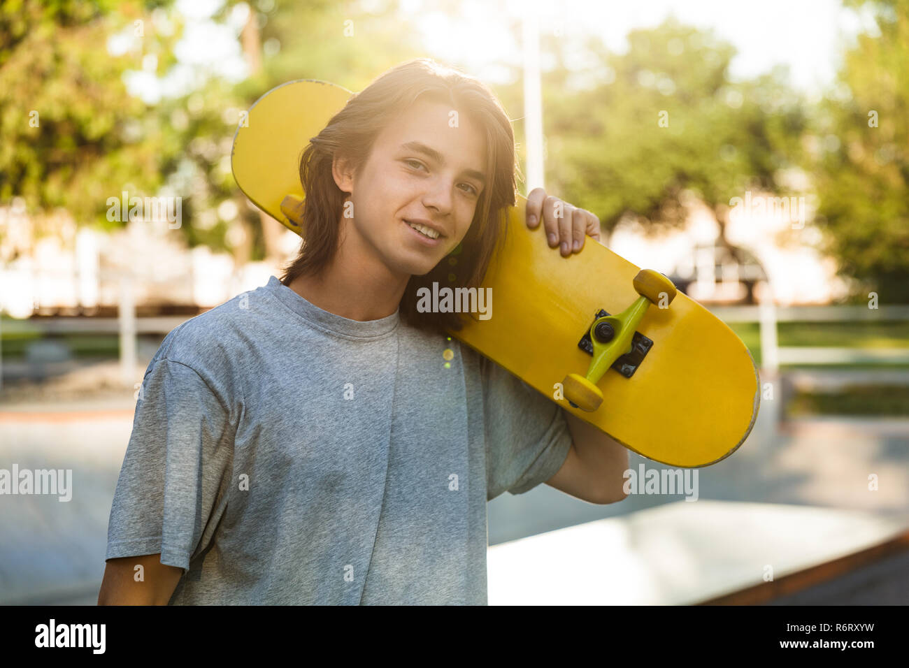 Photo of beautiful skater boy 16-18 in casual wear standing with skateboard  in skate park during sunny summer day Stock Photo - Alamy