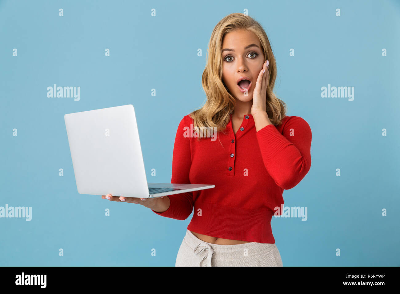 Portrait of shocked or excited woman 20s holding silver laptop isolated