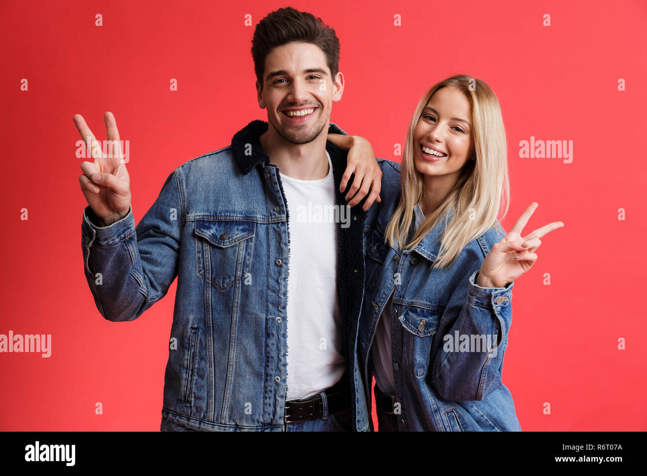Portrait of a happy young couple dressed in denim jackets standing ...