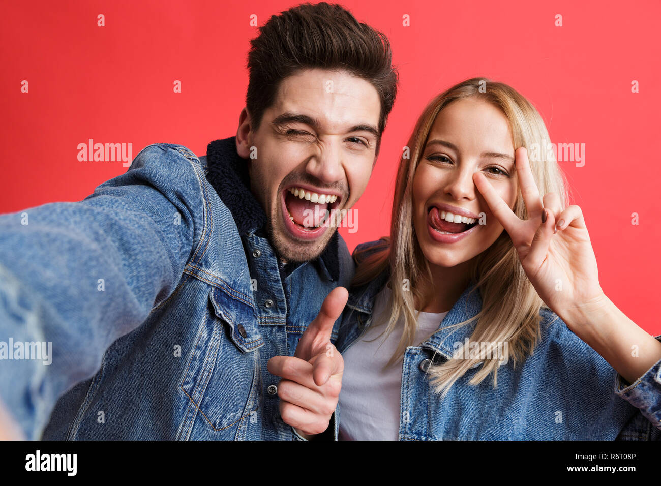 Portrait of a happy young couple dressed in denim jackets standing ...