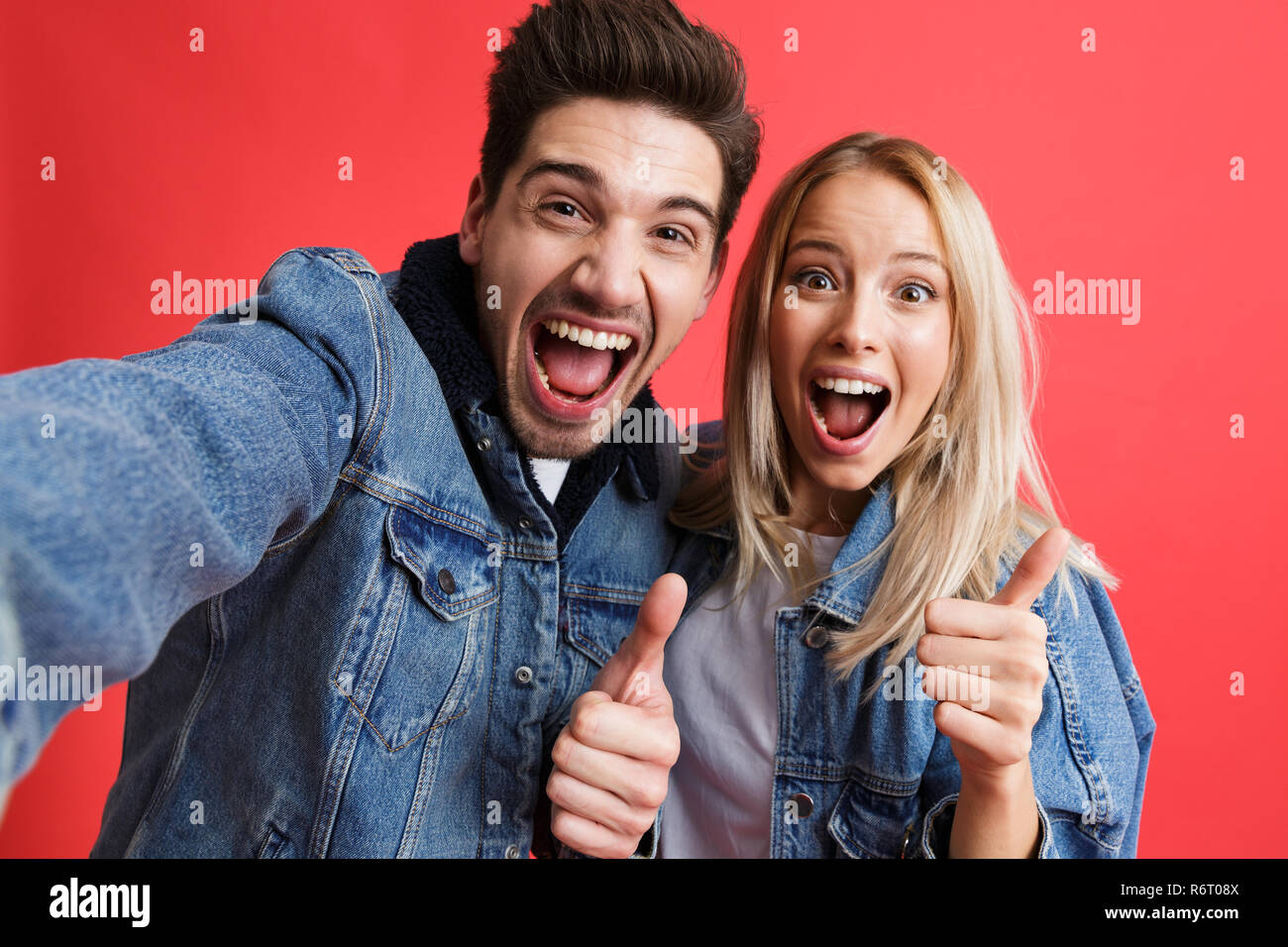 Portrait of a happy young couple dressed in denim jackets standing ...