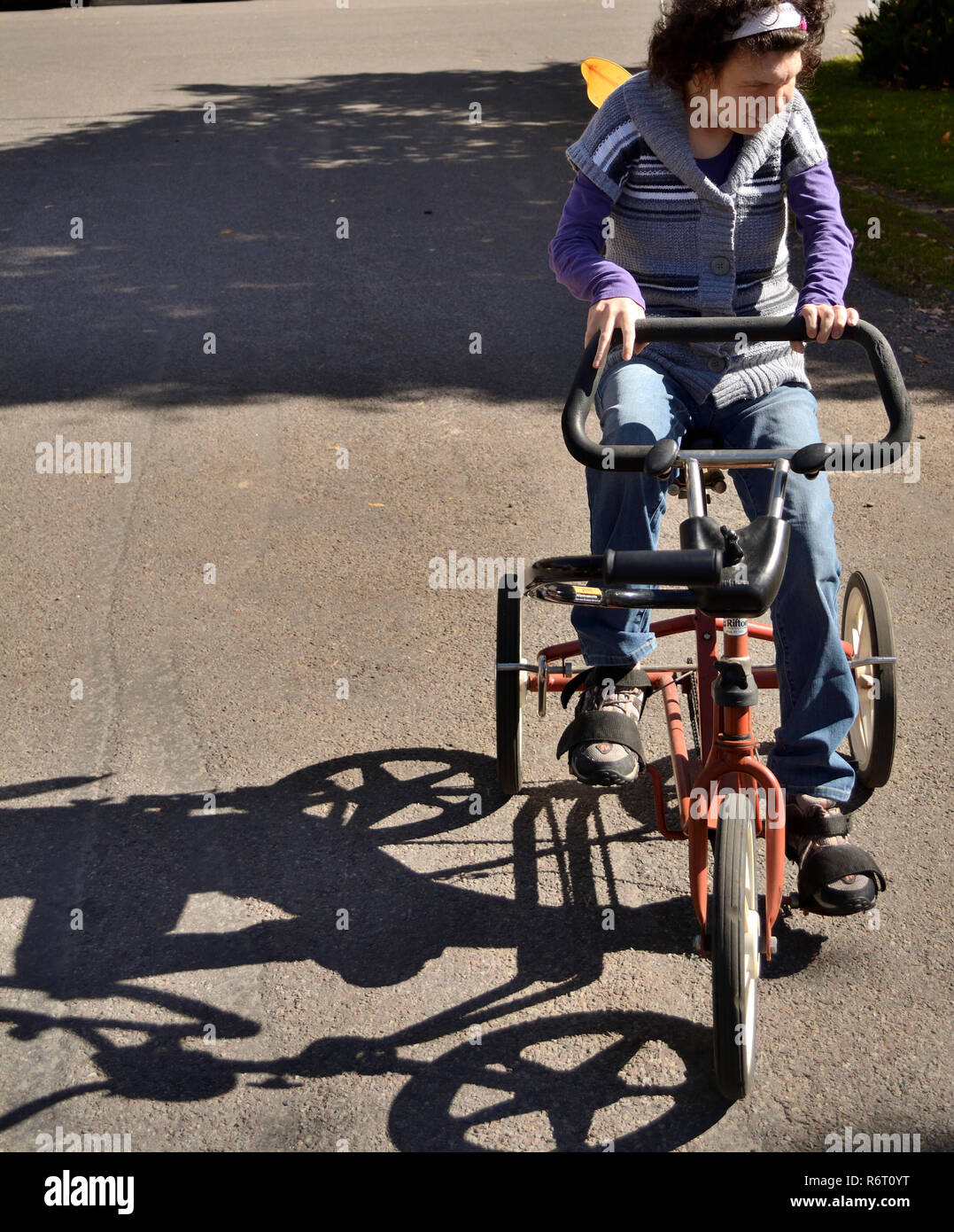 An example of community inclusion, a young woman with special needs rides an adaptive bike in her bike-friendly Colorado community. Stock Photo