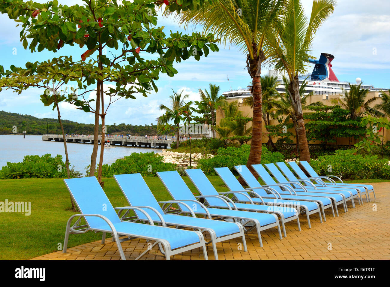 Carnival Splendor is docked behind empty lounge chairs awaiting passengers at Amber Cover, the cruise lines privately owned port. Stock Photo