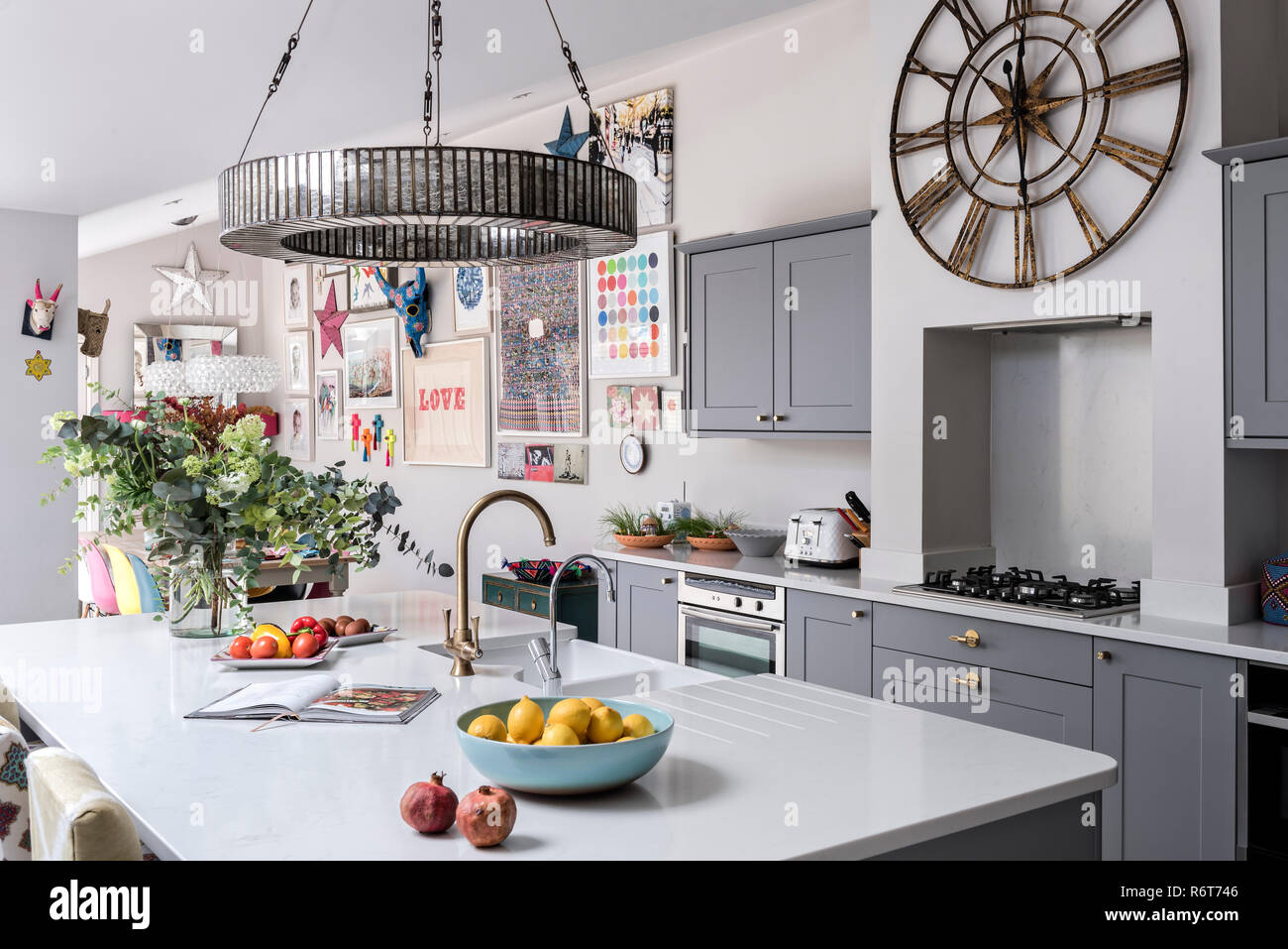 Downton chandelier above reconfigured kitchen with grey fitted units in family home near Barnes Stock Photo