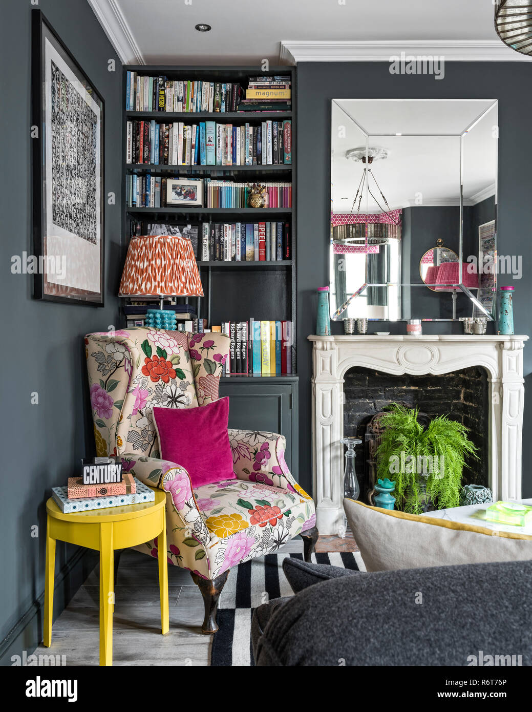 Upcycled wingback armchair with large mirror above fireplace in Richmond home Stock Photo