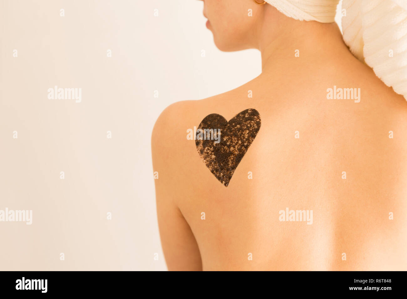 Close up woman with coffee scrub in a heart shape on her back and shoulder. Skin care concept, exfoliation Stock Photo