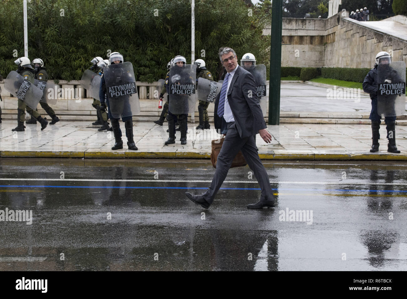 Athens, Greece. 6th Dec, 2018. A businessman passes by riot police ...