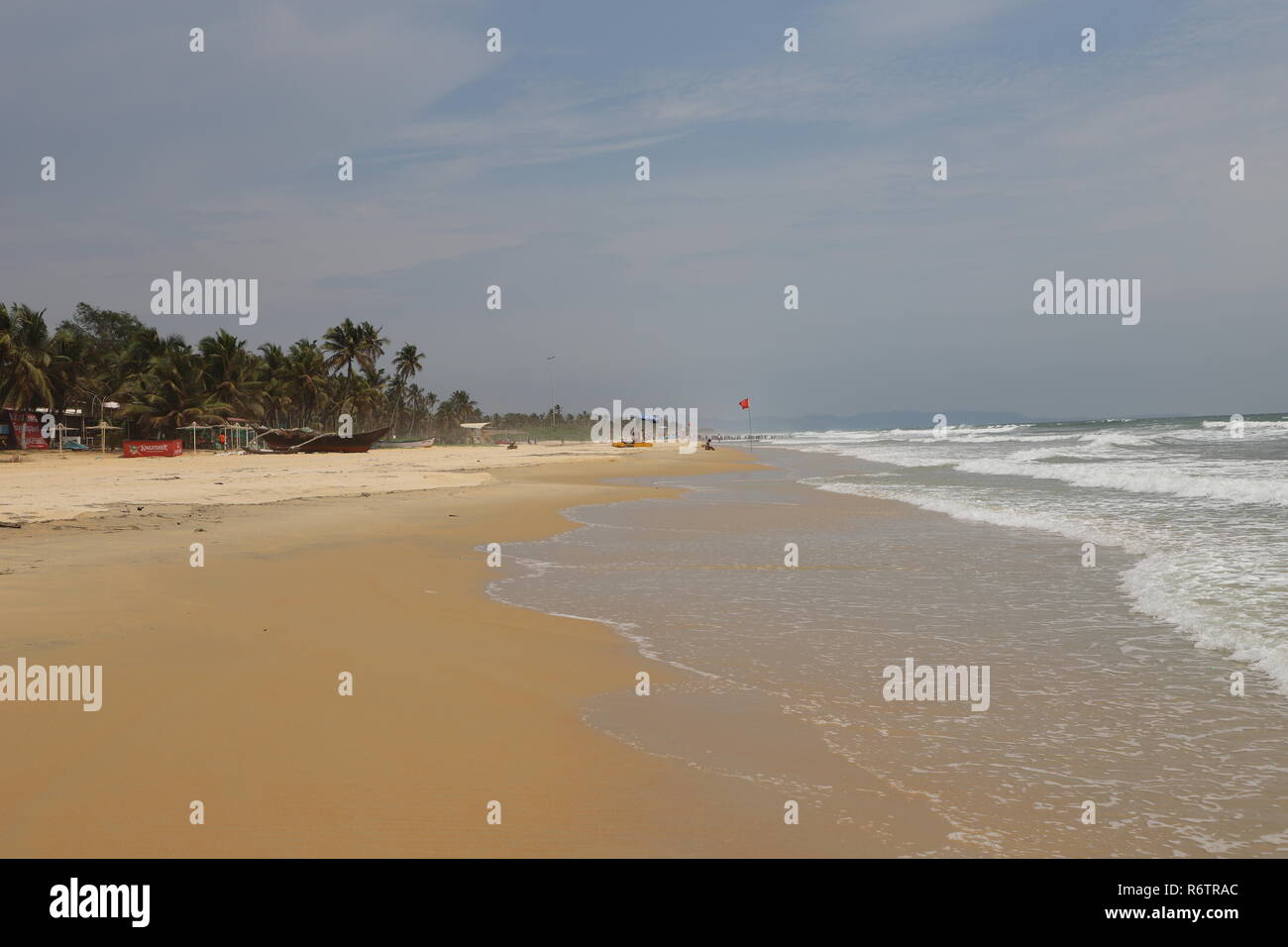 Classic Beach picture in Goa consisting of beautiful waves touching the yellow sand softly with an amazing view of the coconut trees Stock Photo