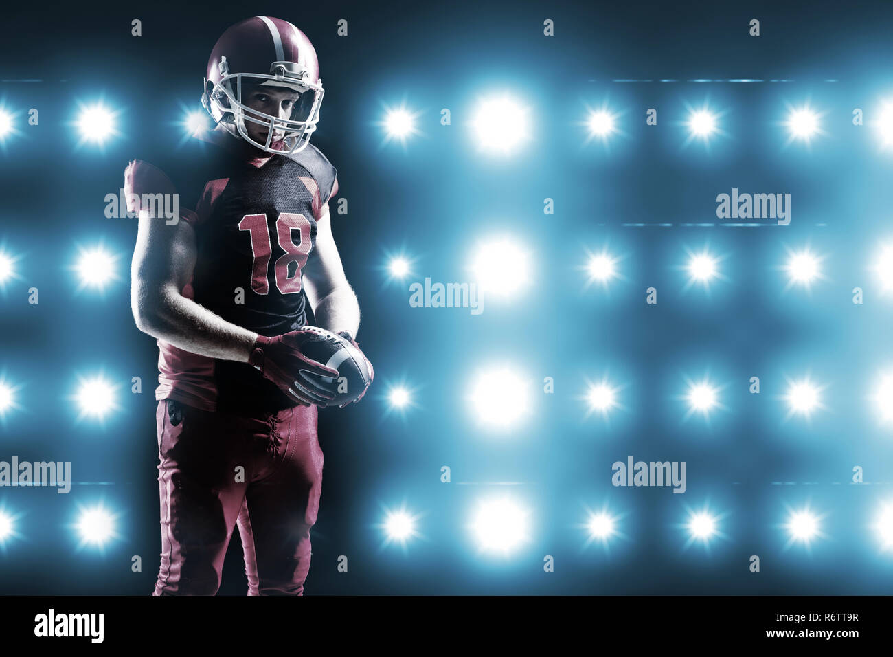 Digitally generated image of blue spotlight  against american football player in helmet holding rugby ball Stock Photo