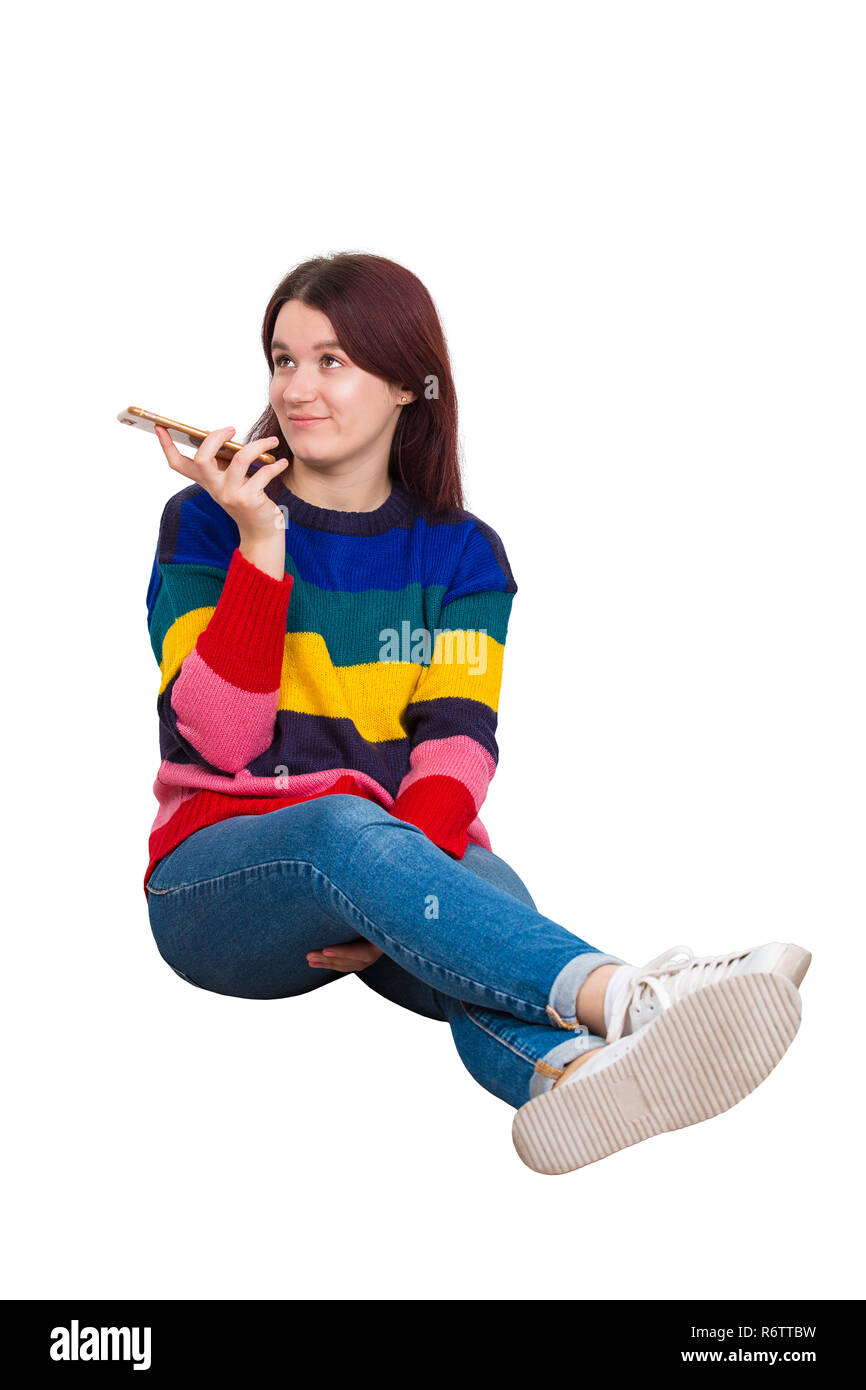 Casual young woman relaxing on the floor holding mobile phone and imagining looking away isolated over white background Stock Photo