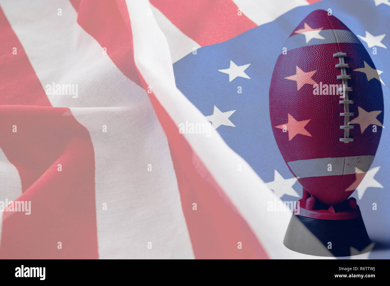 Brown American football on tee against close-up of crumbled american flag Stock Photo