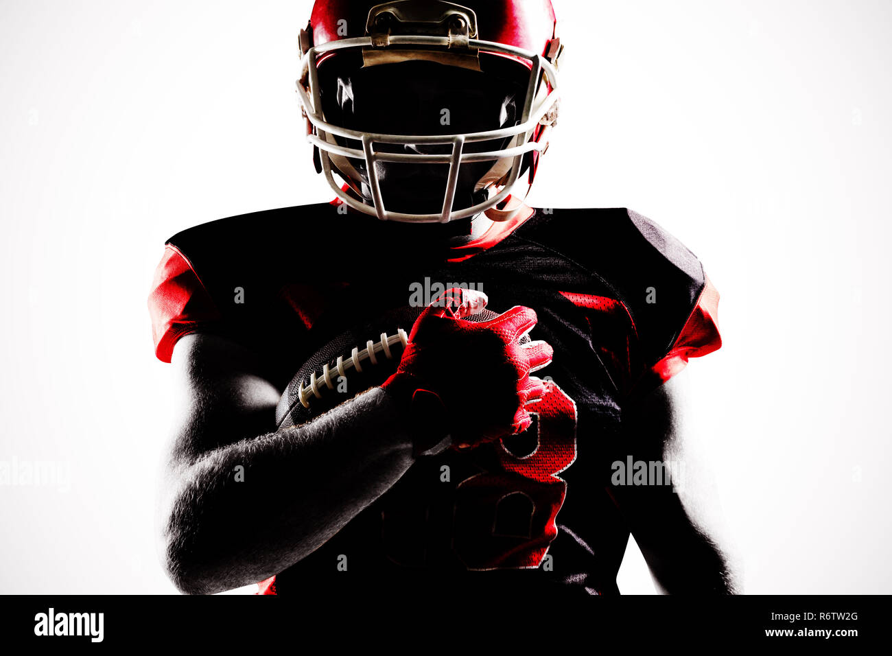 American football player in helmet holding rugby ball with hand raised ...