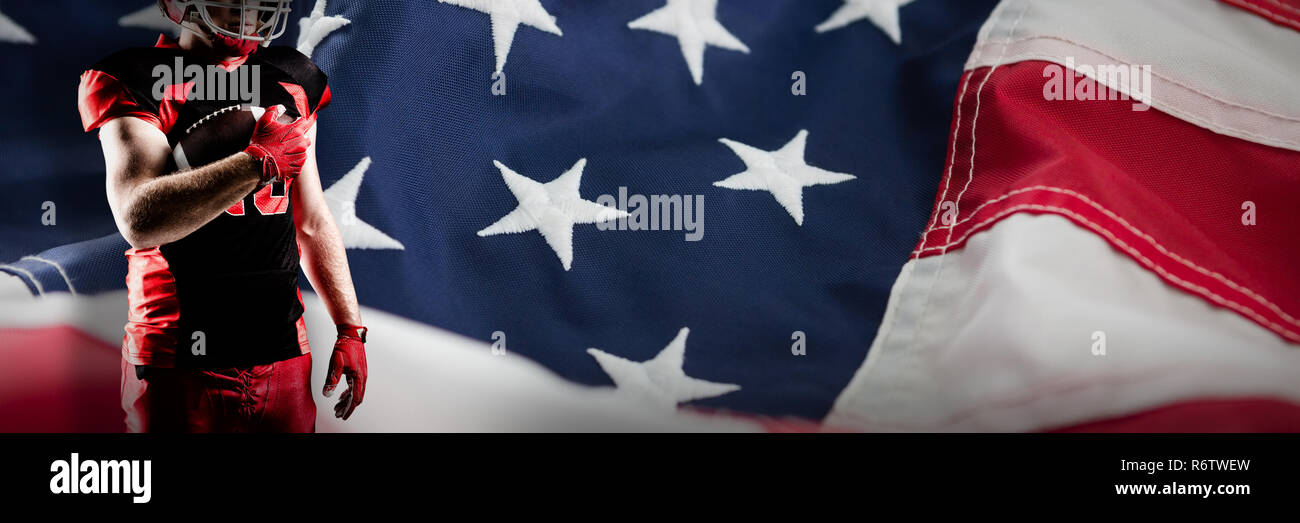 American football player in helmet holding rugby ball against full frame of american flag Stock Photo