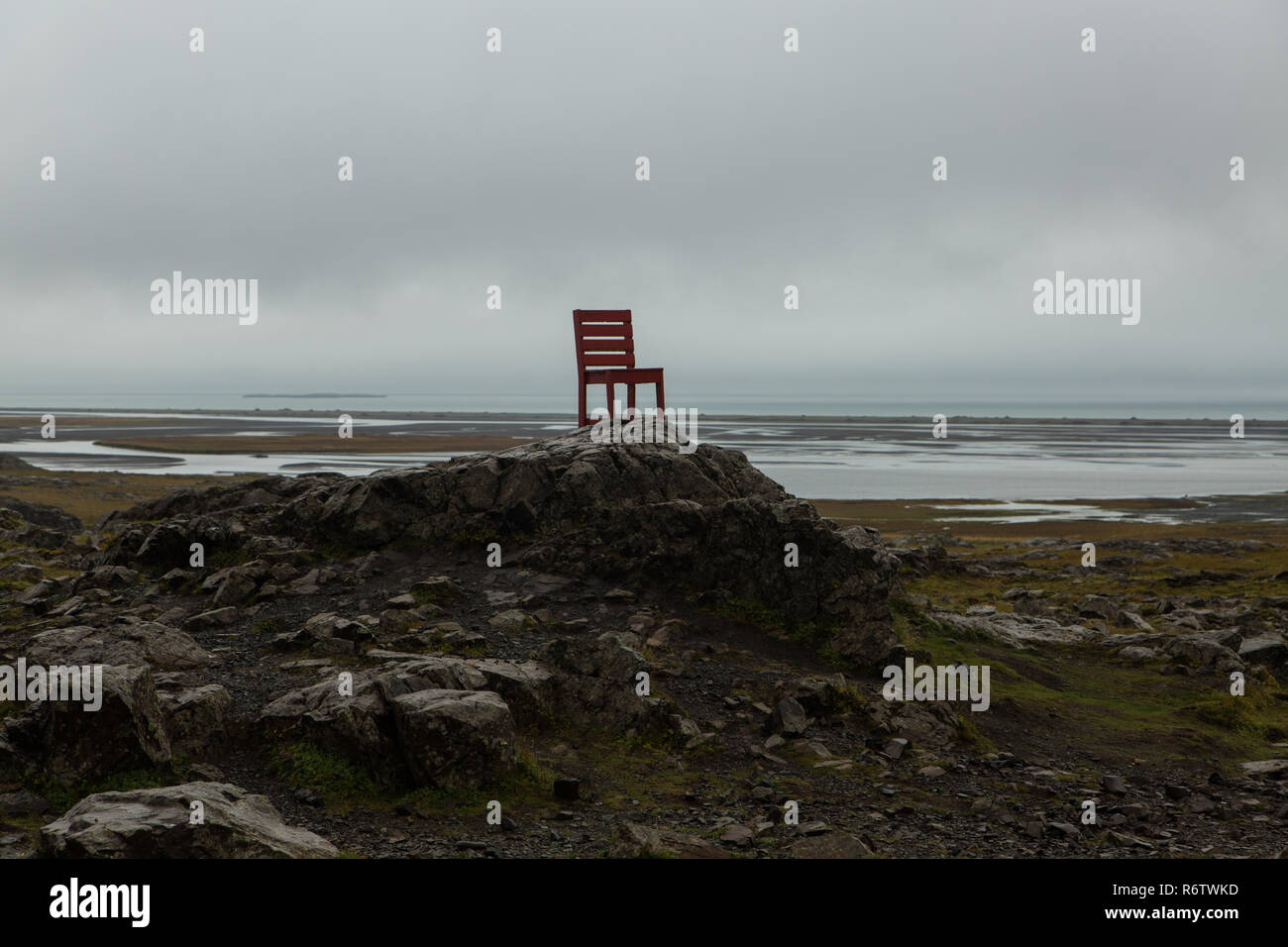 A wooden big red chair on a rock at seaside near Eystrahorn, East Iceland Stock Photo