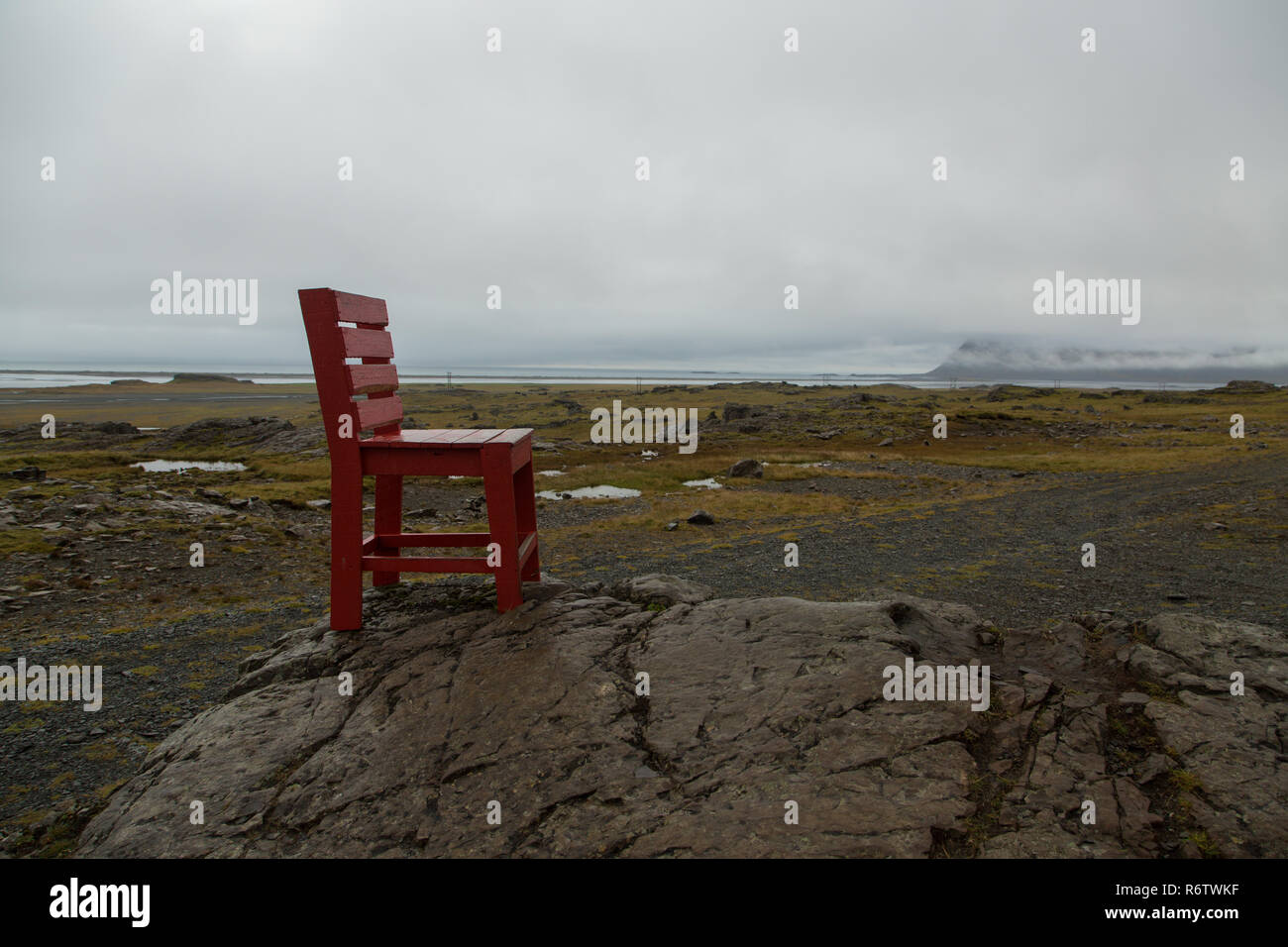 A wooden big red chair on a rock at seaside near Eystrahorn, East Iceland Stock Photo