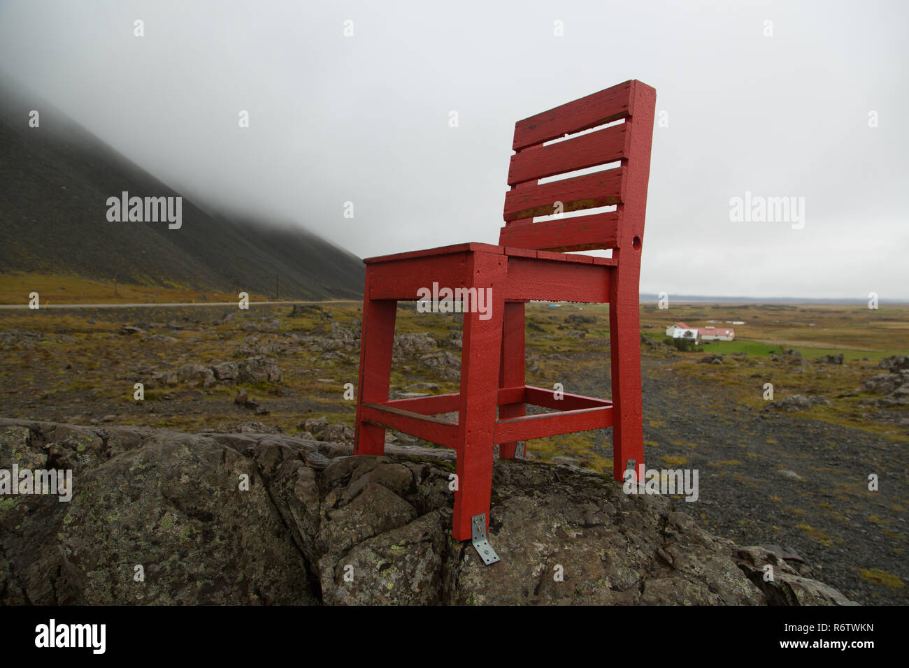 A wooden big red chair on a rock at seaside near Eystrahorn, East Iceland Stock Photo