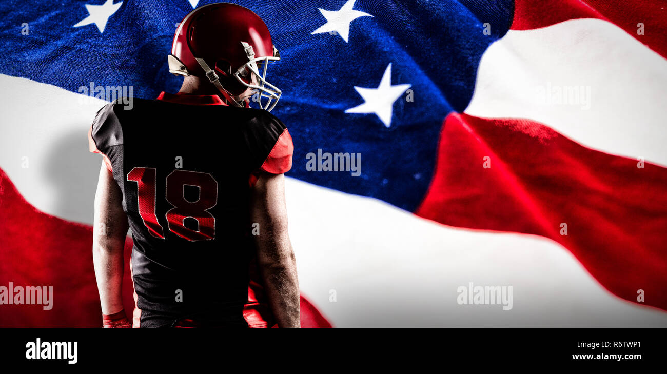 American football player standing in rugby helmet against american flag with stars and stripes Stock Photo
