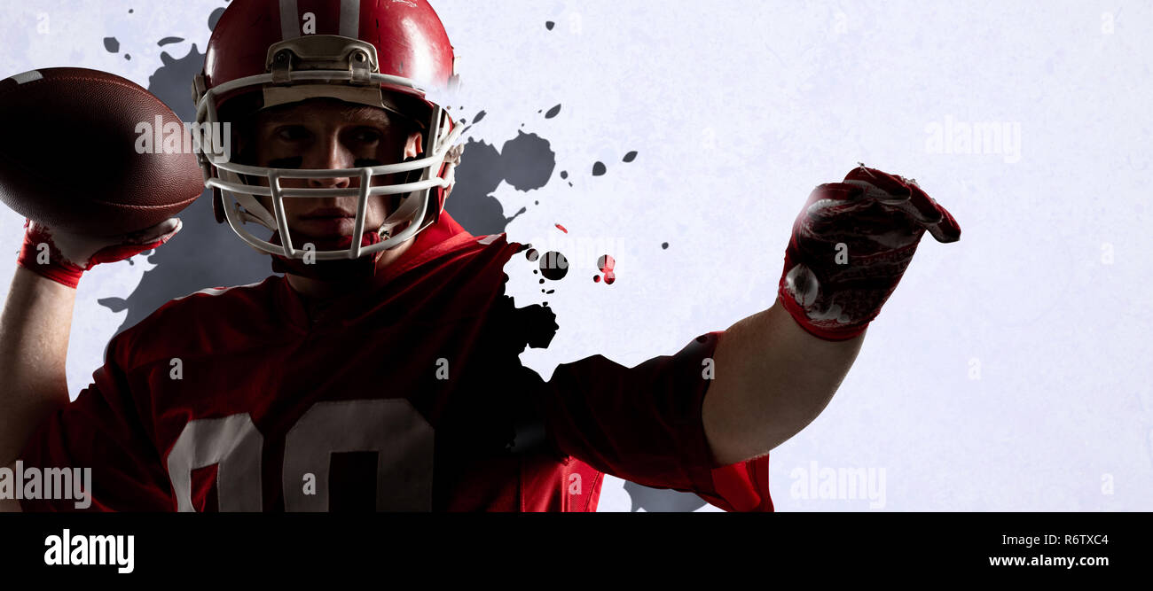 American football player standing with helmet preparing to throw ball against grey vignette Stock Photo