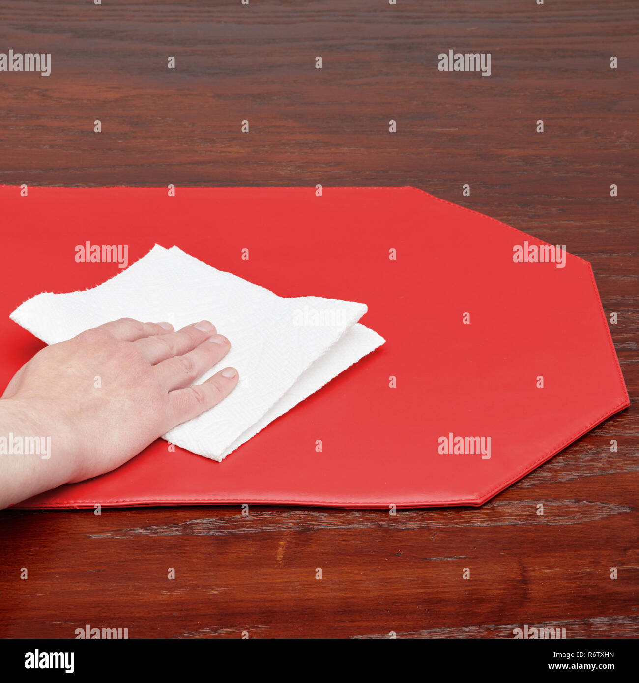 Cleaning Octagon Shaped Red Kitchen Place Mat on Wood Surface Stock