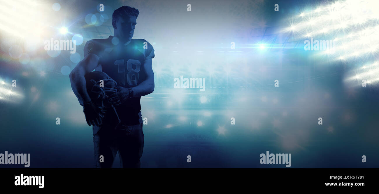 American football player holding rugby helmet against american football arena Stock Photo