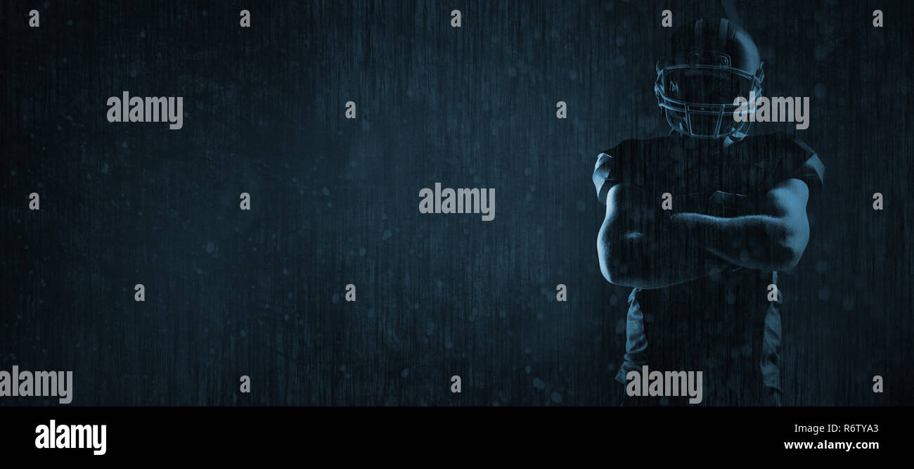 American football player standing with arms crossed against old weathered wall Stock Photo