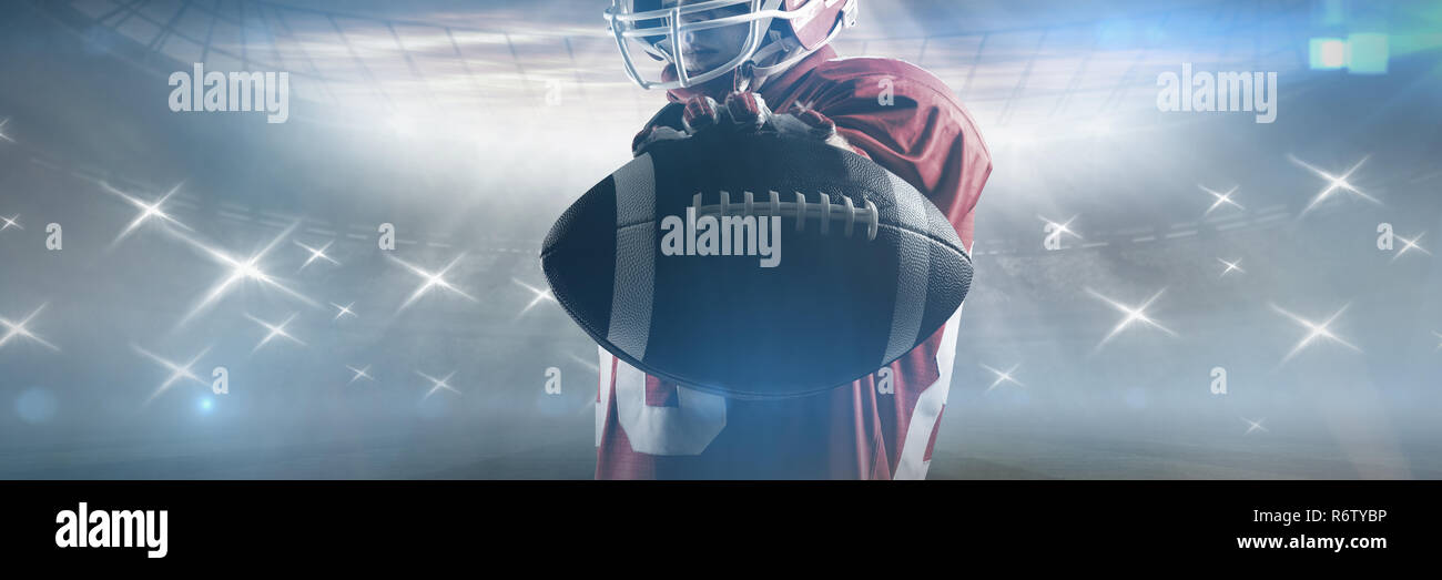 Young American football player standing in rugby helmet and holding rugby ball Stock Photo