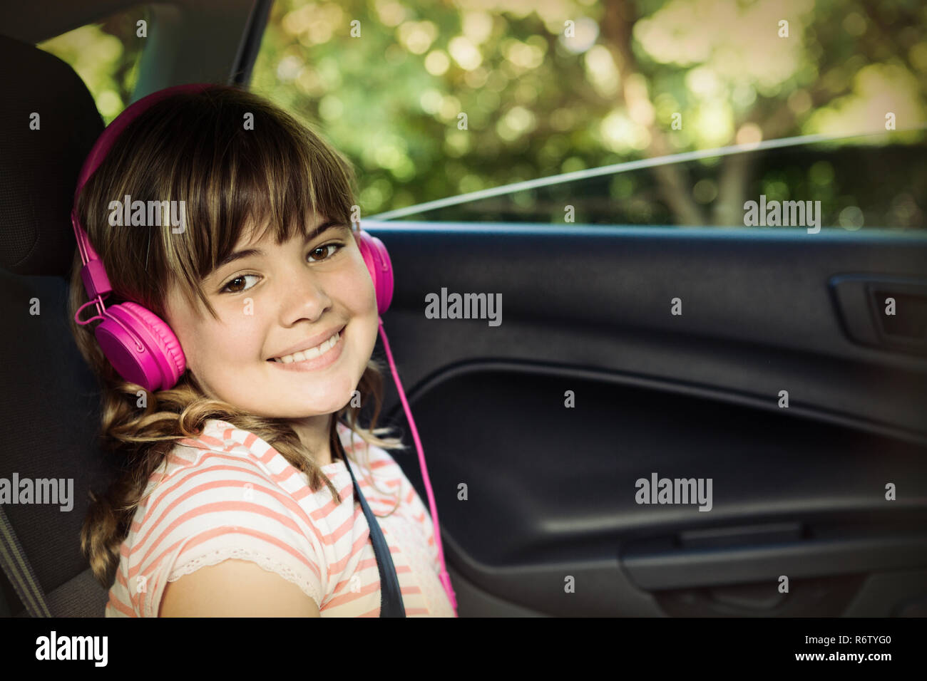 Portrait of smiling teenage girl with headphones in the back seat of car Stock Photo Alamy