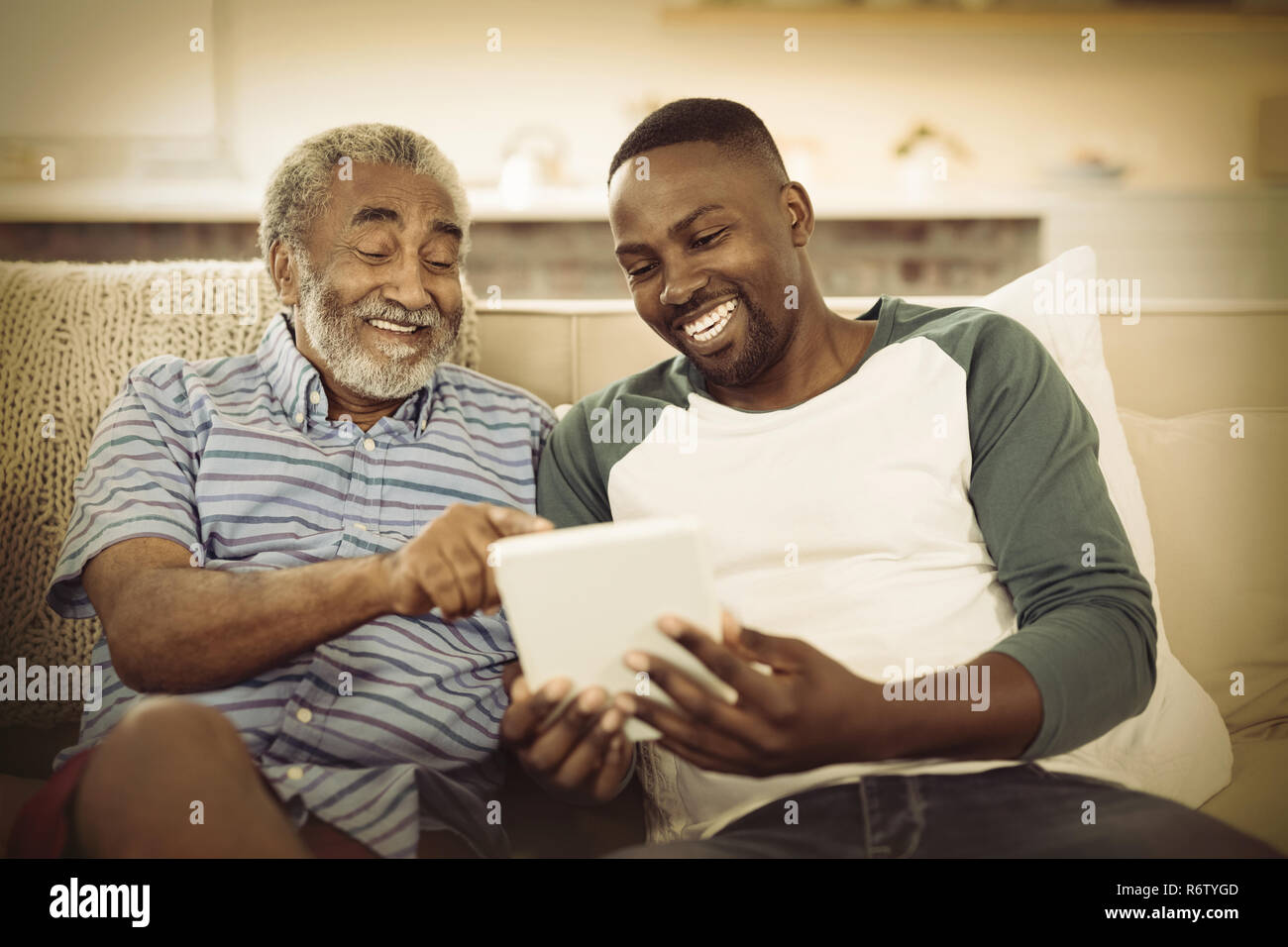 Smiling father and son using digital tablet in living room Stock Photo