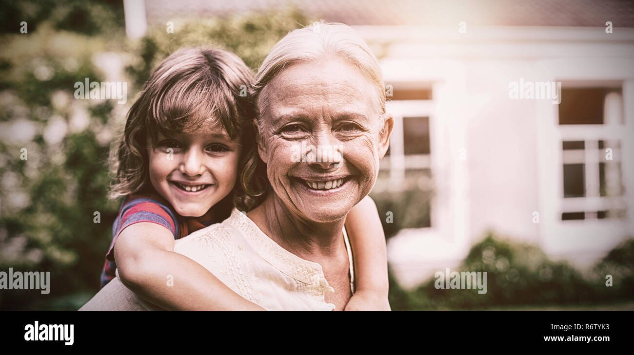 Granny piggybacking grandson in yard Stock Photo