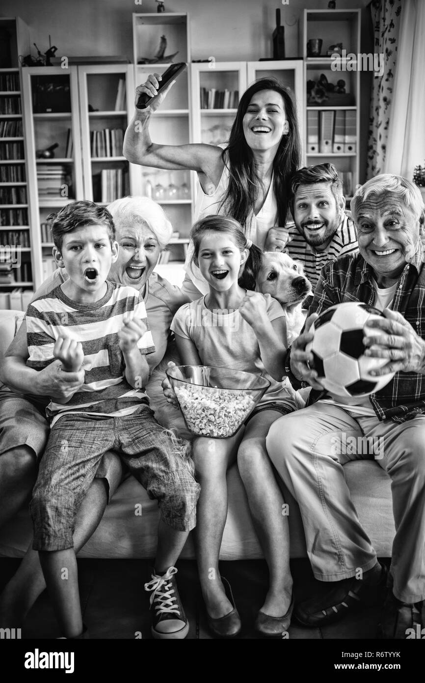 Happy multi-generation family watching soccer match on television in living room Stock Photo