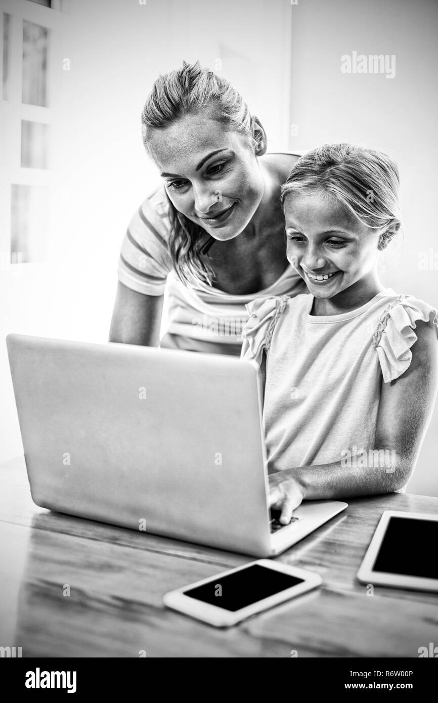 Mother assisting daughter in uising laptop at home Stock Photo