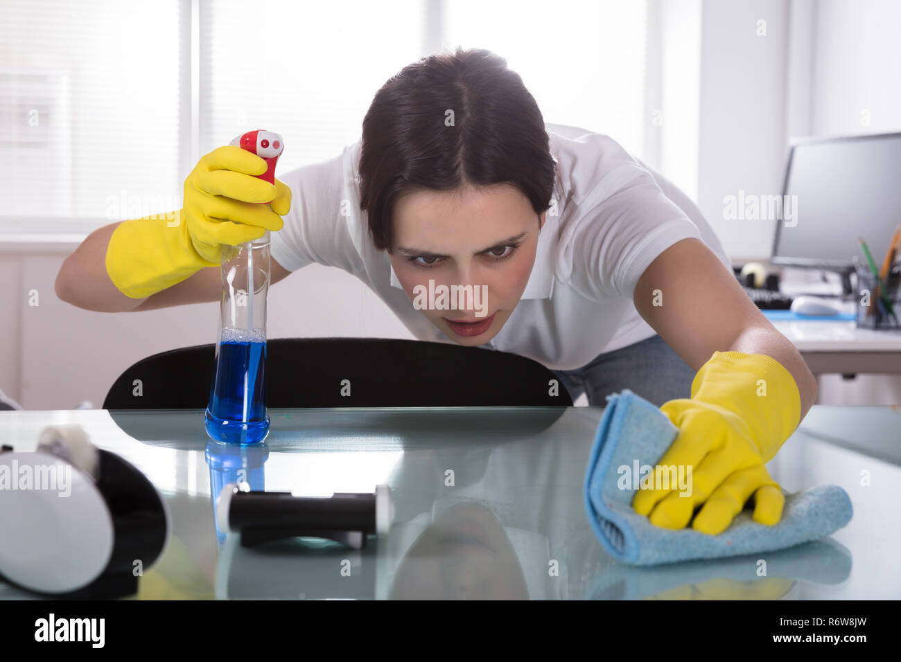 Female Janitor Cleaning Desk In Office Stock Photo Alamy