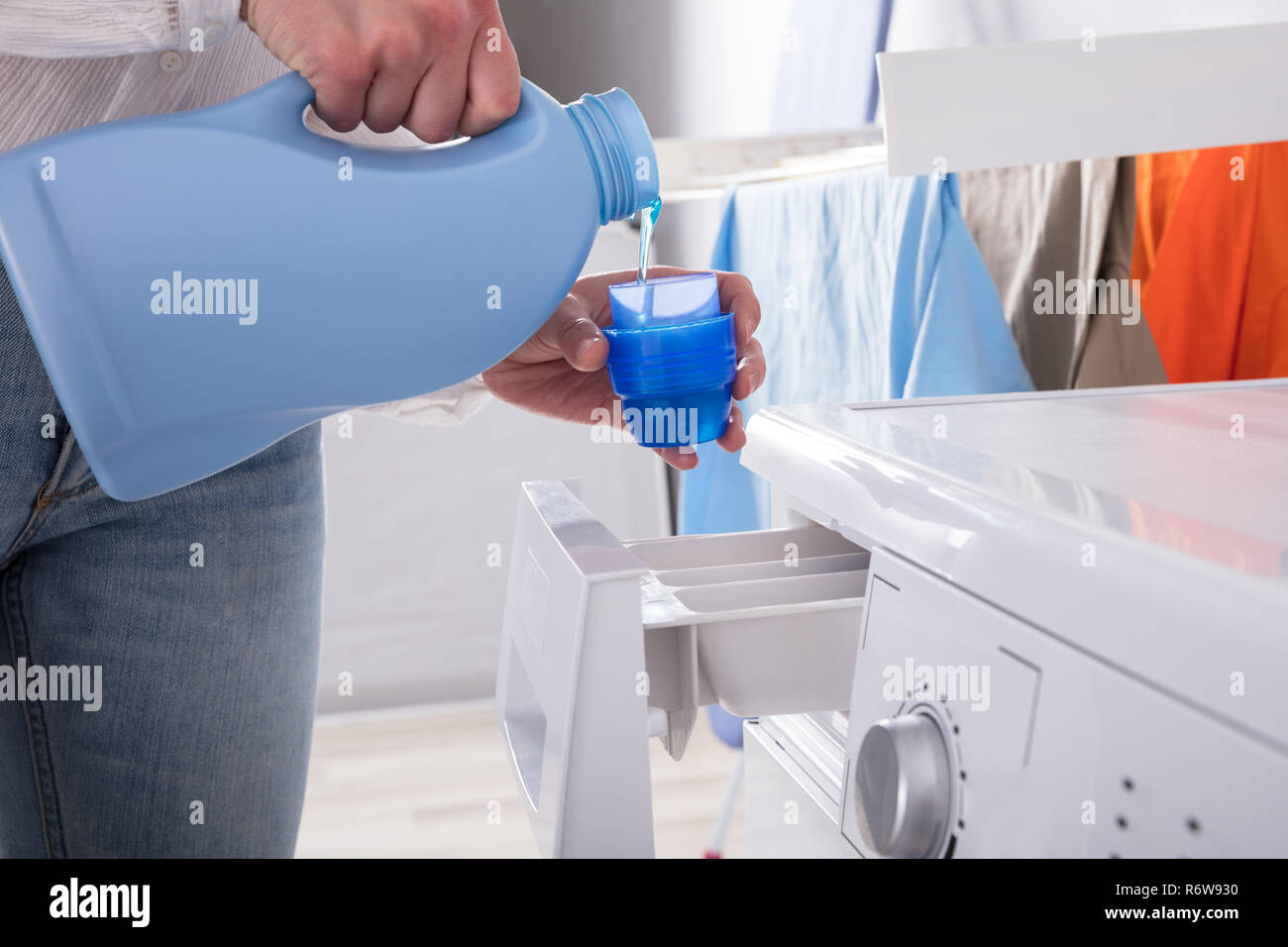 Person Pouring Detergent In Lid Stock Photo