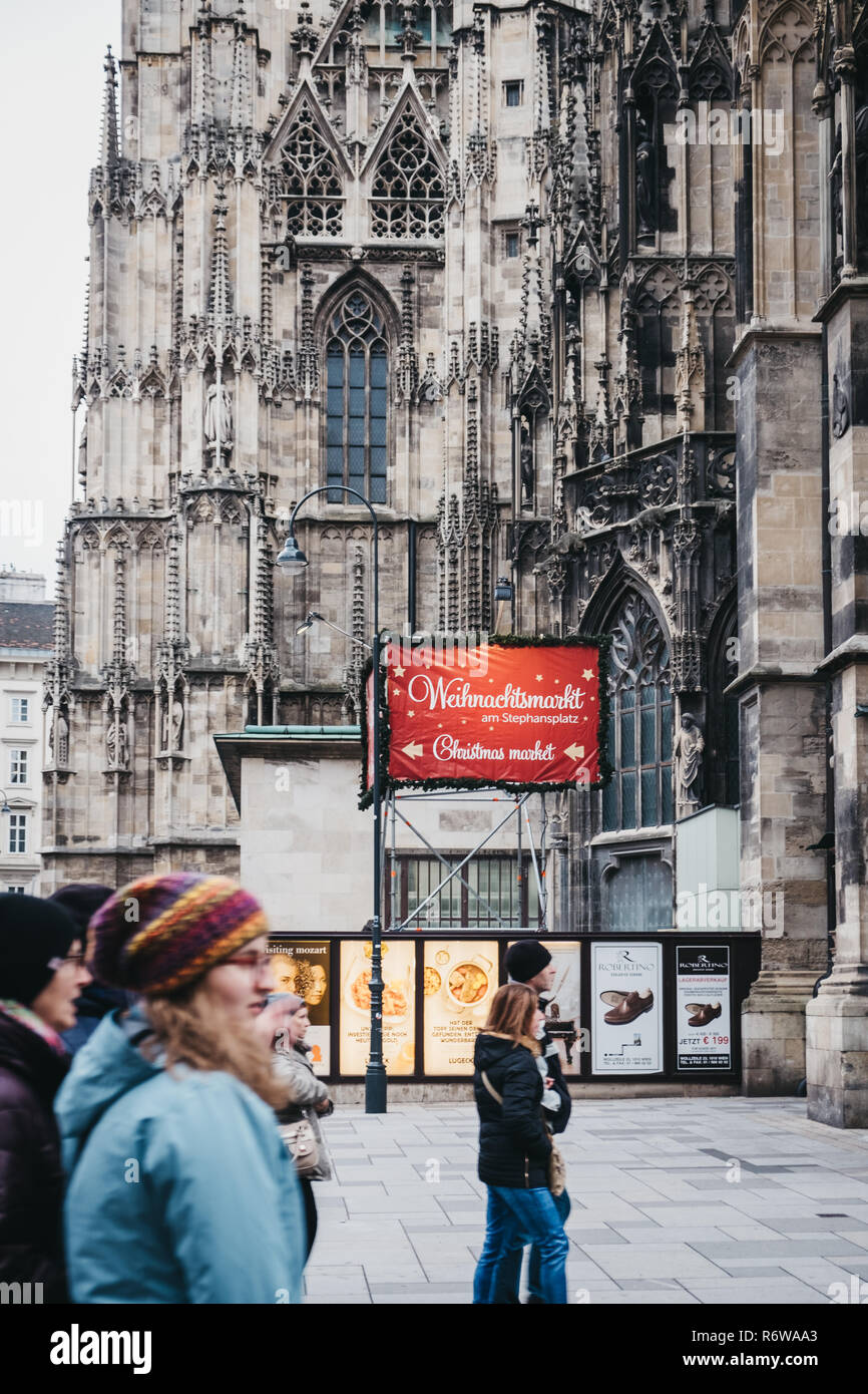Vienna, Austria - November 24, 2018: People walking past directional sign to Christmas market stall near St. Stephen Cathedral, the most important rel Stock Photo