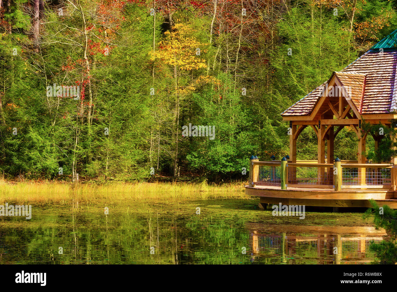 Colorful fall colors reflect along the shoreline where a gazebo sits in