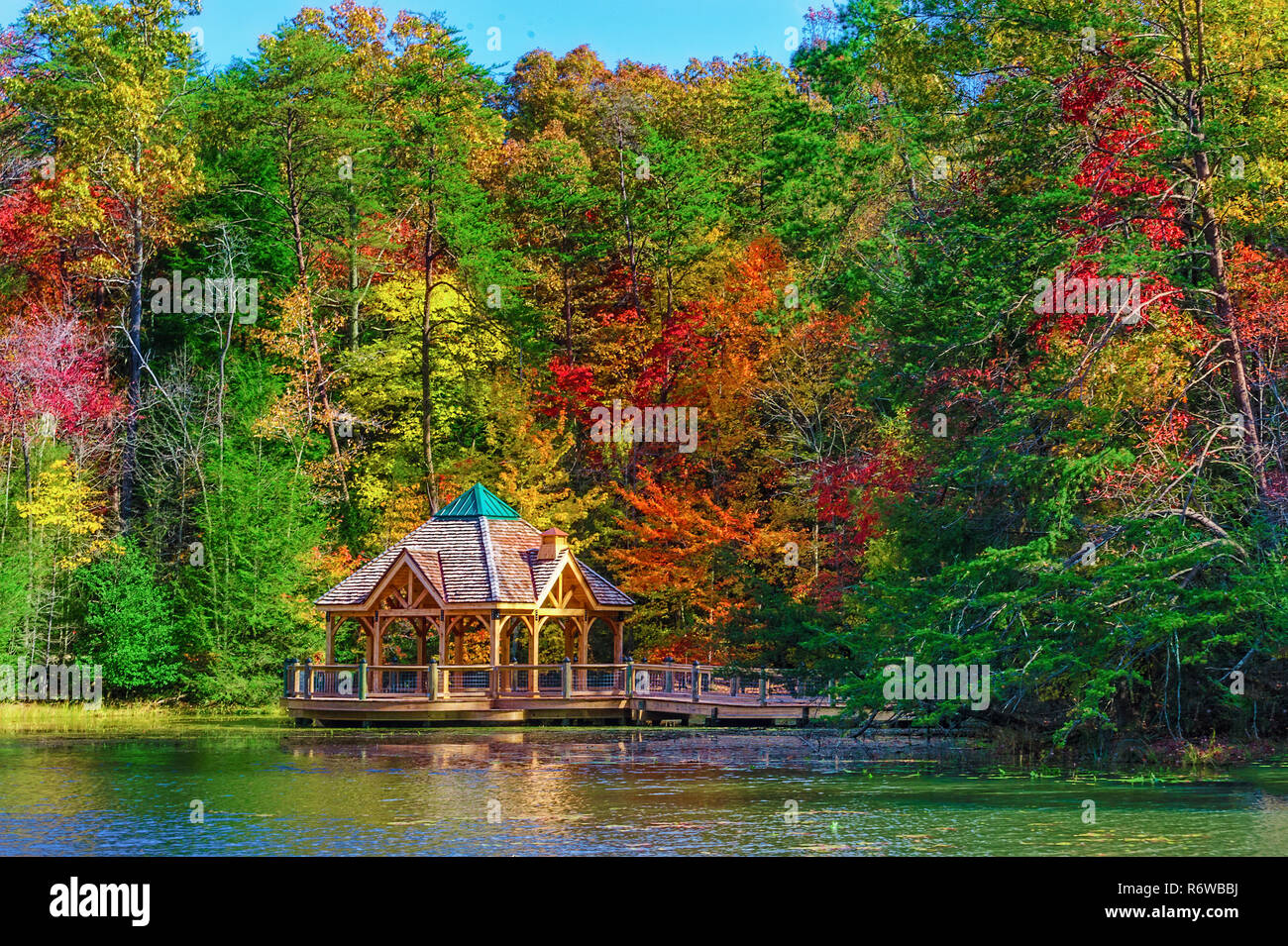 Colorful fall colors reflect along the shoreline where a gazebo sits in