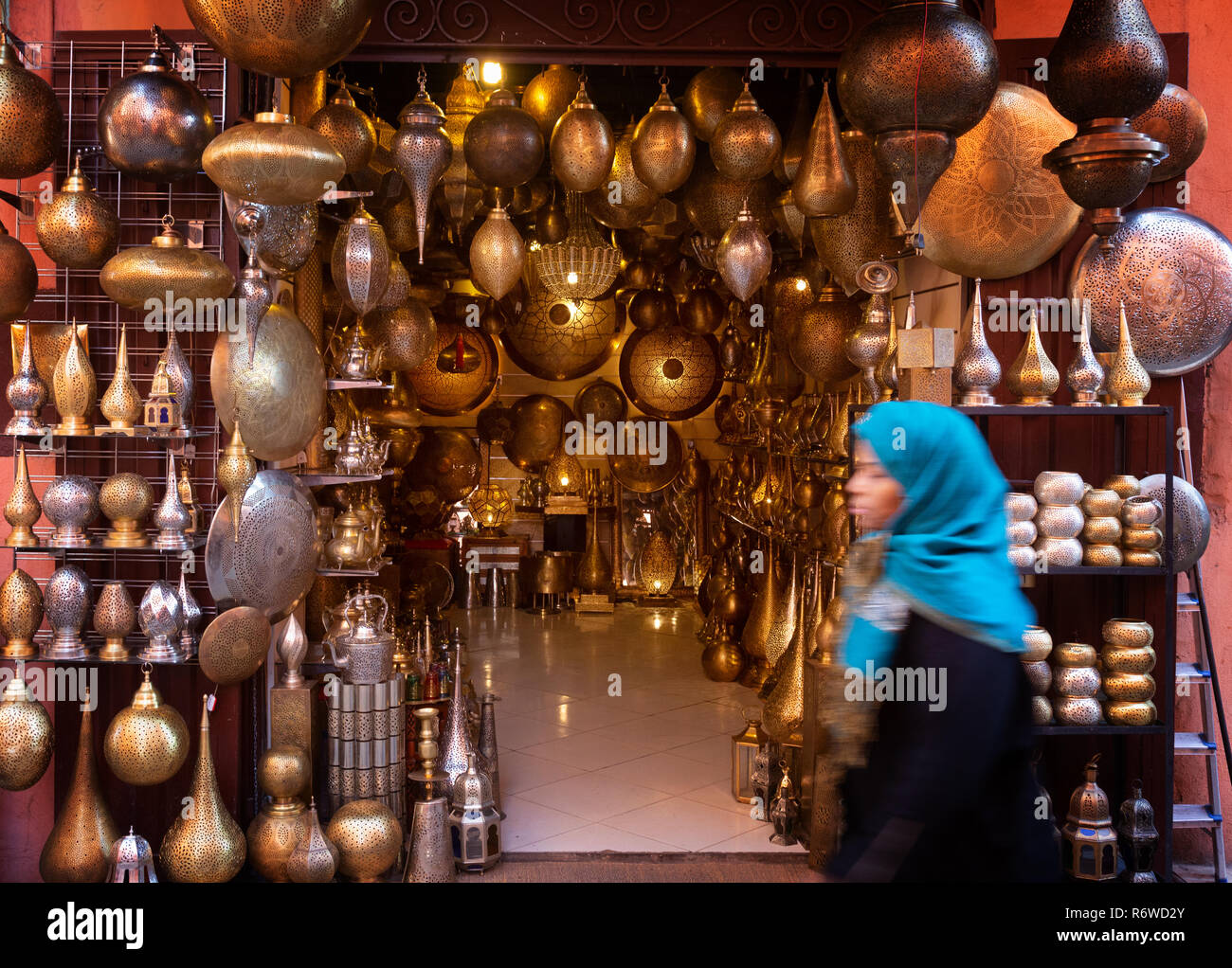 Marrakech souk - a local arab woman walking past a craft shop, Marrakesh medina, Morocco North Africa Stock Photo