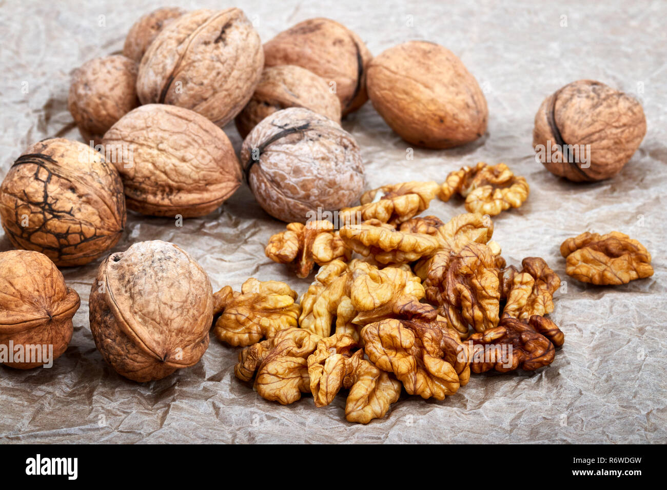 Walnut kernels with whole nuts in background, selective focus. Stock Photo