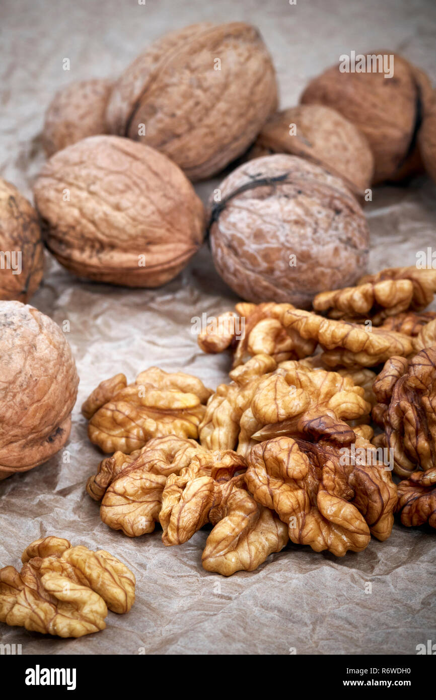 Walnut kernels with whole nuts in background, selective focus. Stock Photo