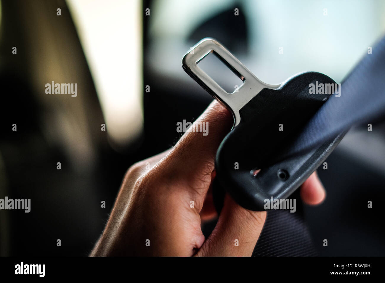 Hand of driver holding seat belt (safety belt) lock in car before