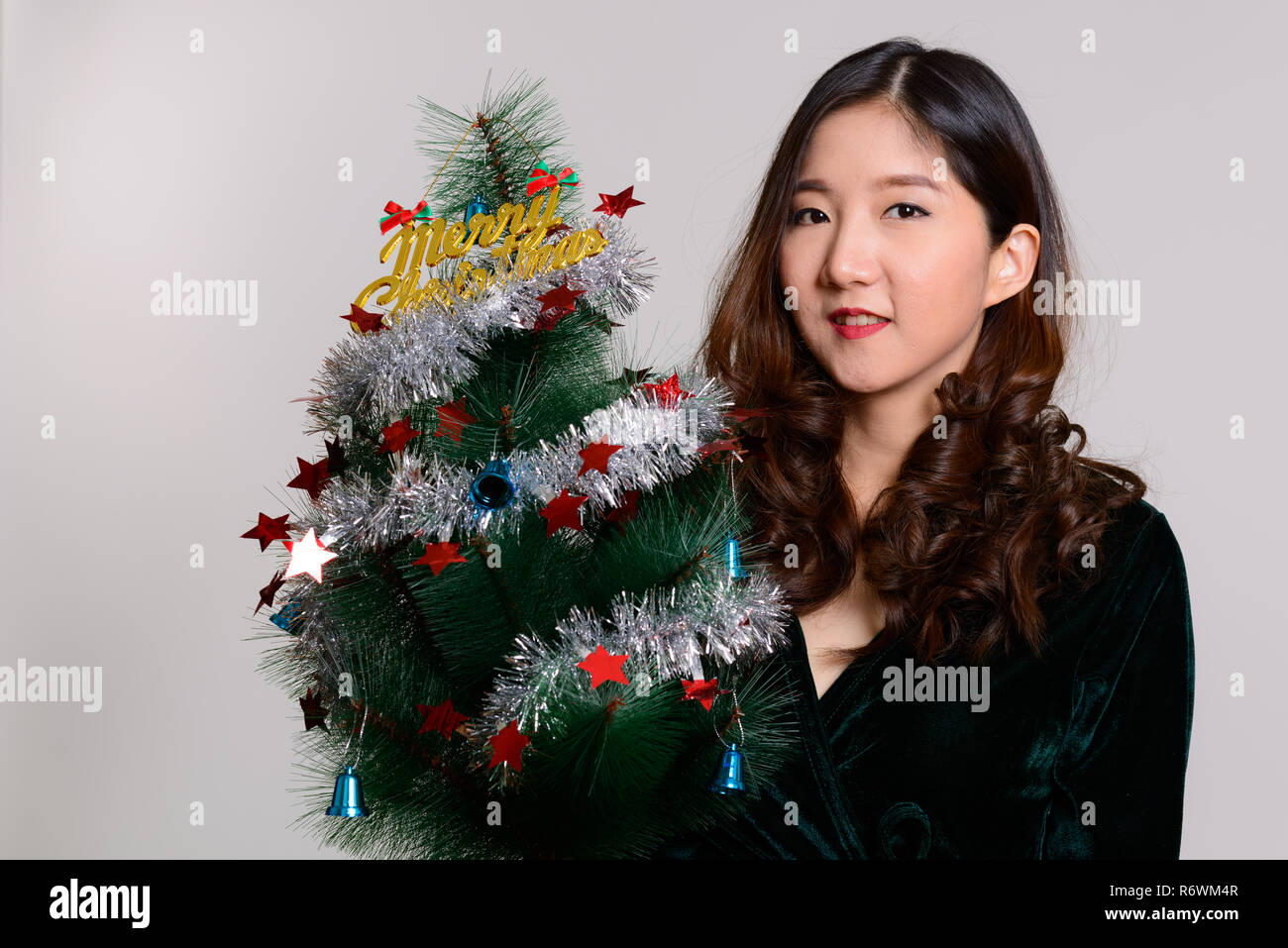 Young happy Asian woman holding Merry Christmas tree  Stock Photo