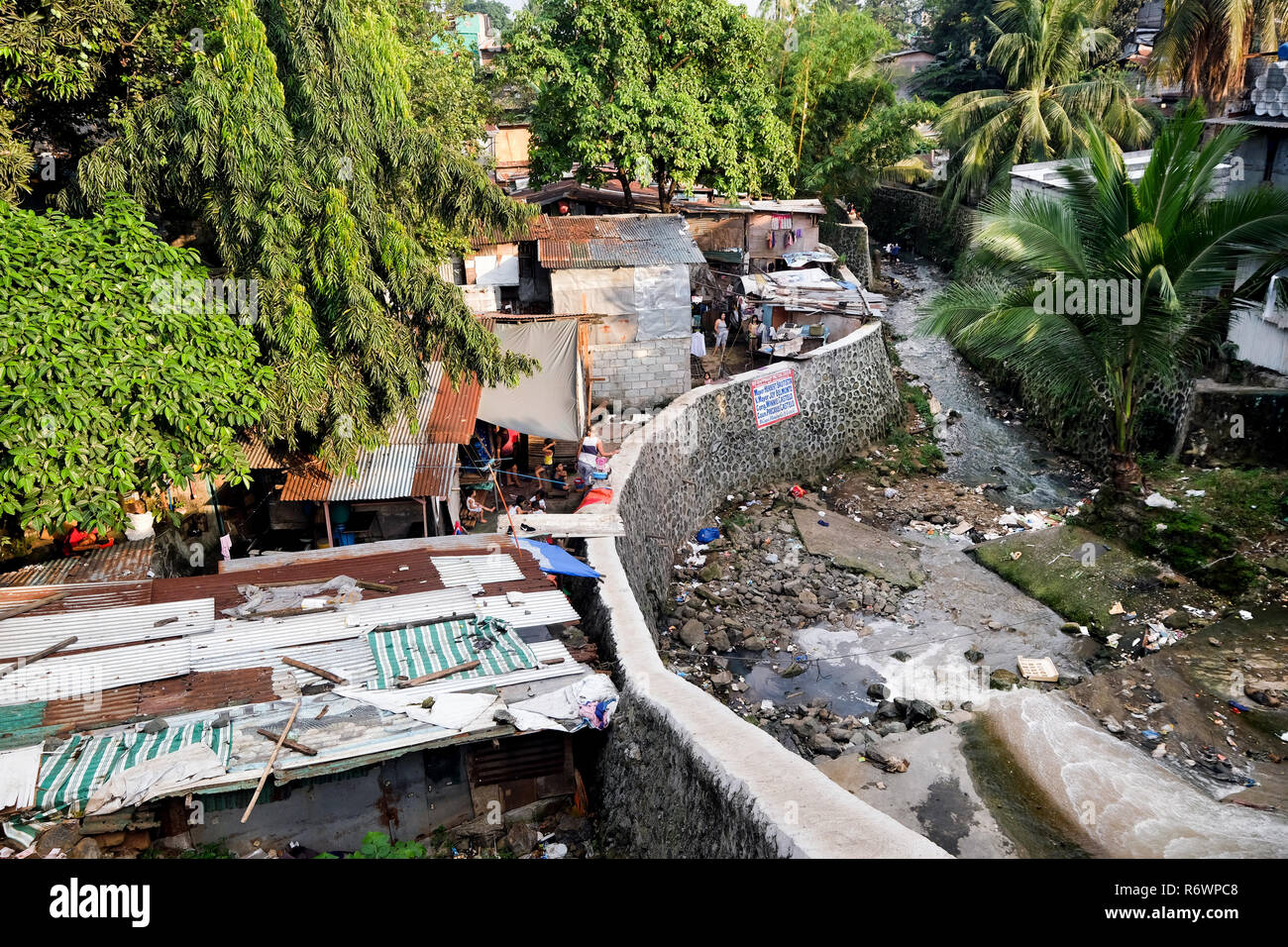 Huts of a slum next to a polluted watercourse in Quezon City, Metro Manila, Philippines Stock Photo