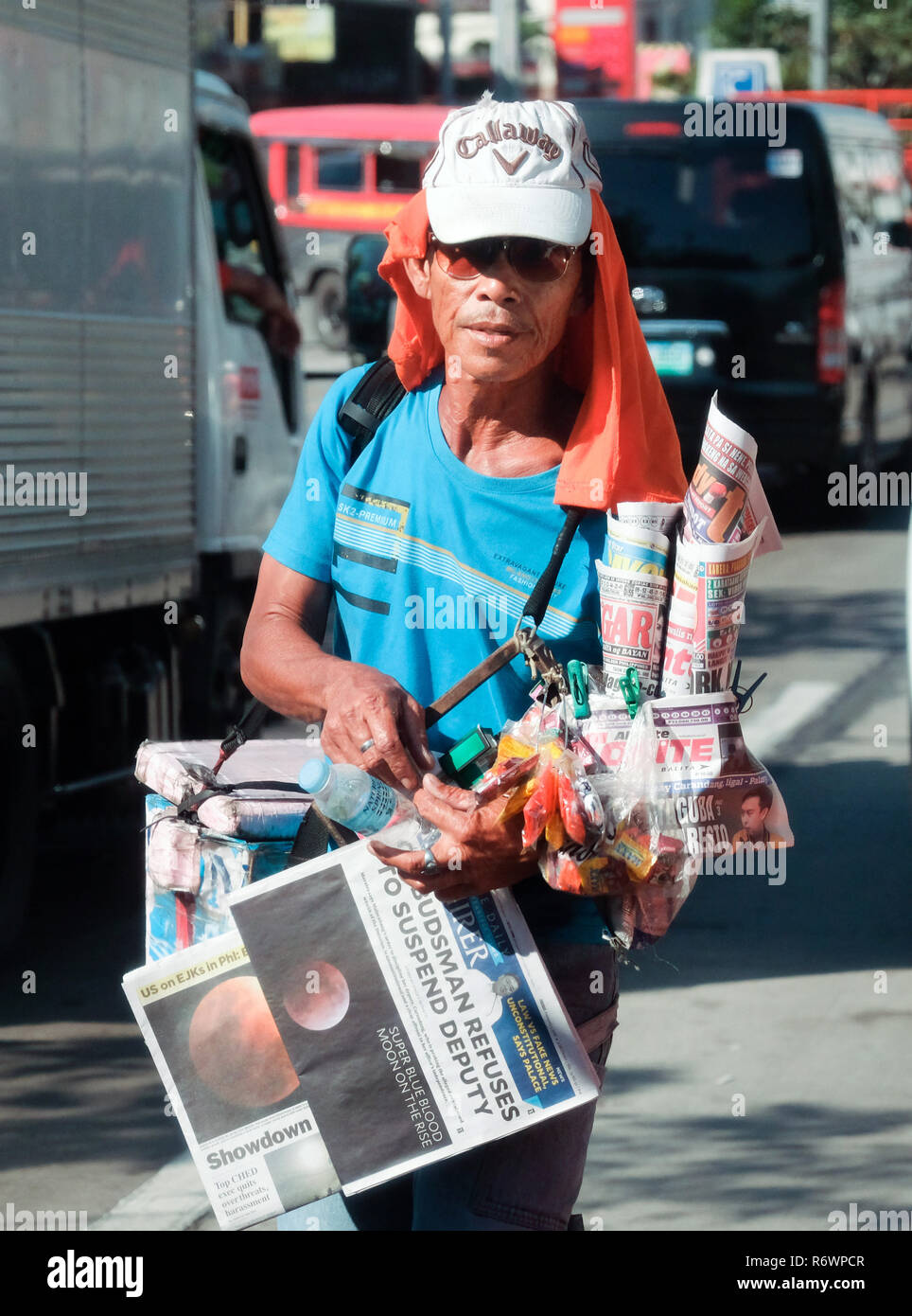 Street vendor between cars in a traffic jam trying to sell newspaper to drivers and passengers in Quezon City, Metro Manila, Philippines Stock Photo